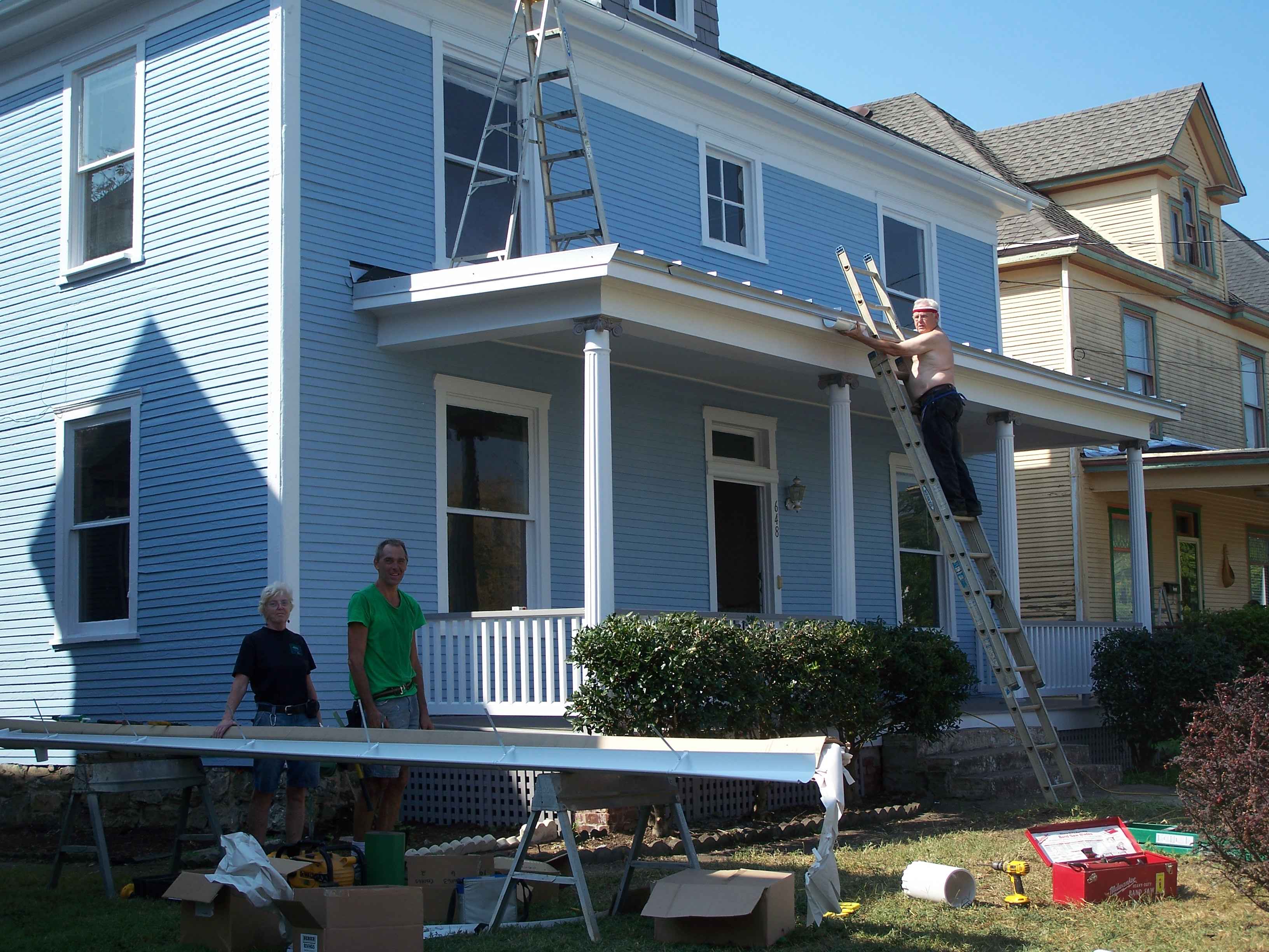 Crew installing new seamless gutters on a two-story home