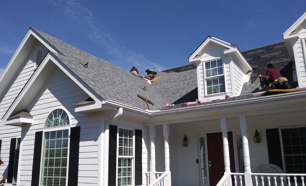 Crew installing new gray shingles on single-family home